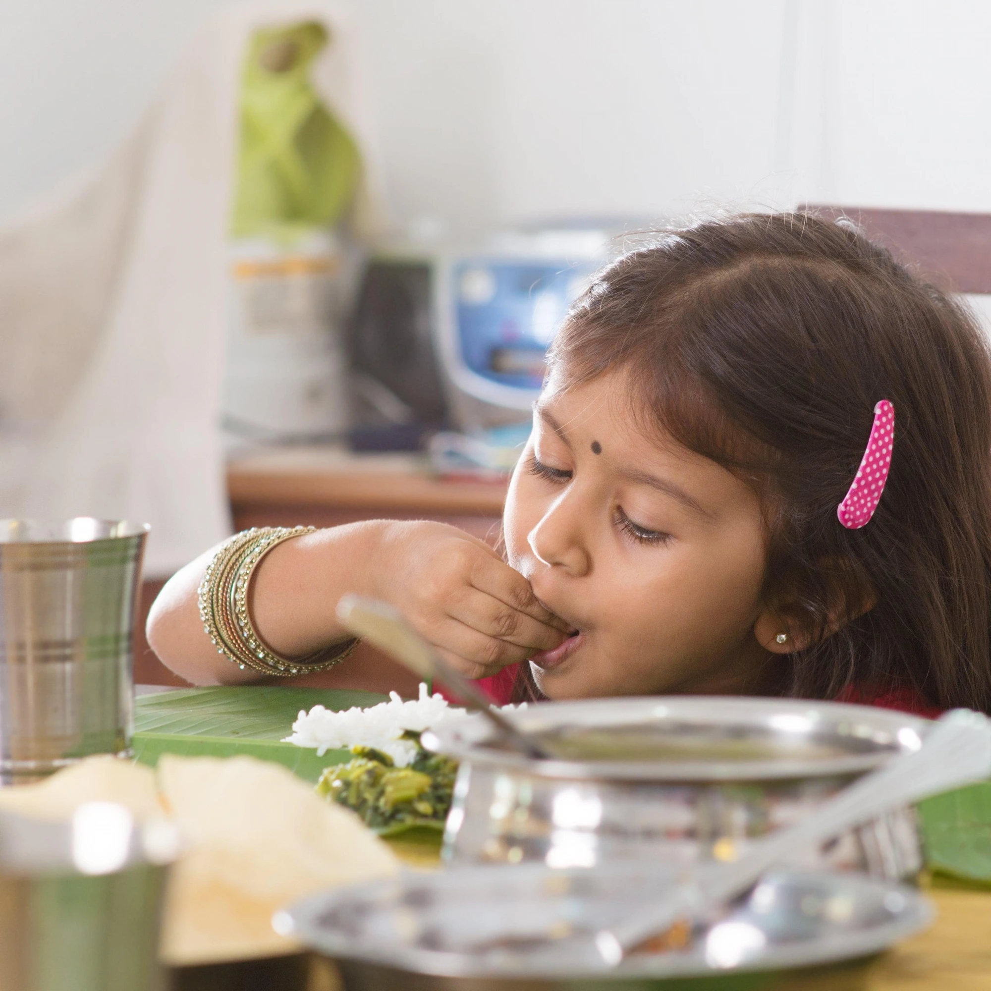 Little girl happily eating rice and sabzi at home