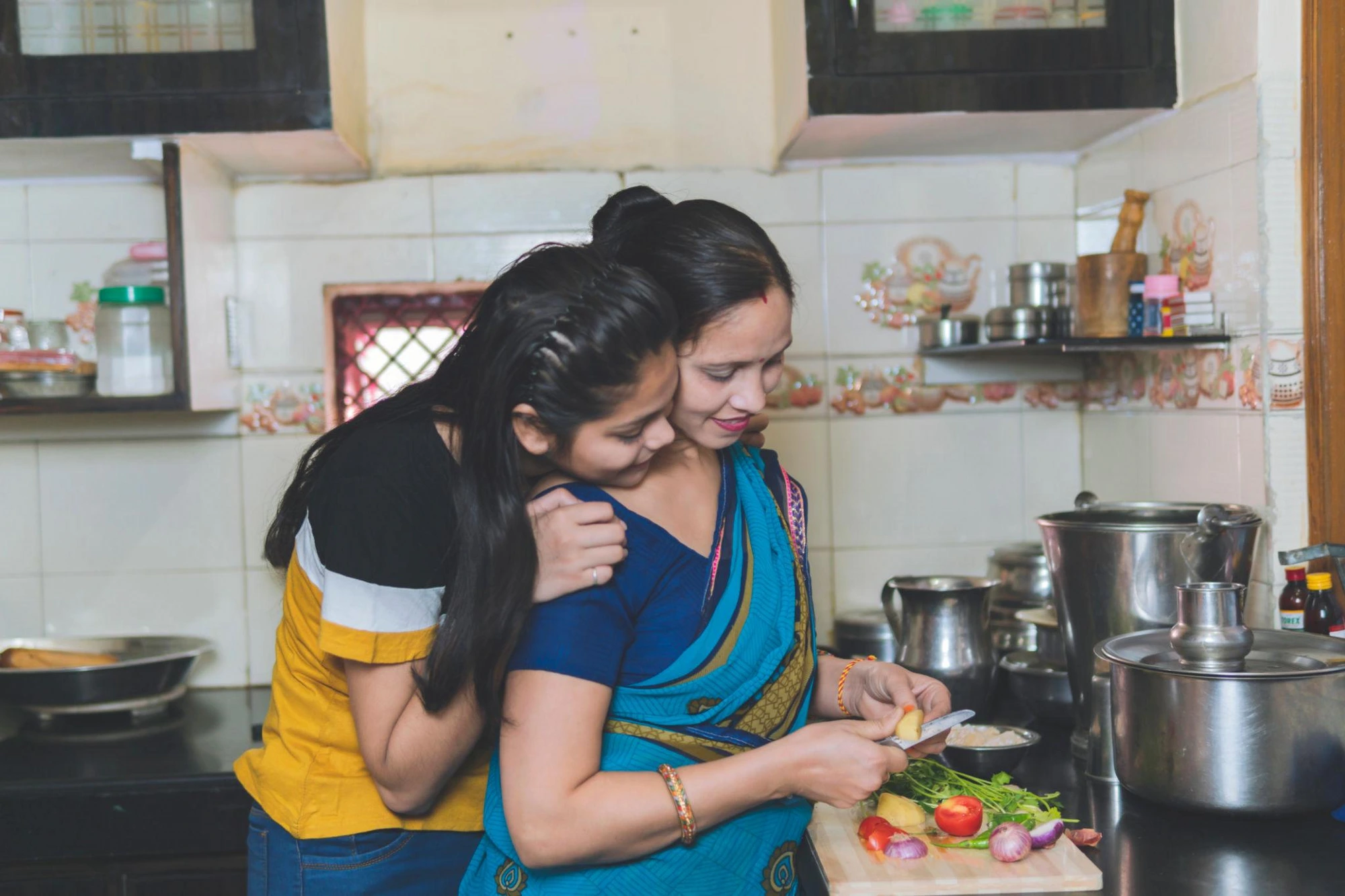 Mother chopping fresh vegetables with her daughter beside her